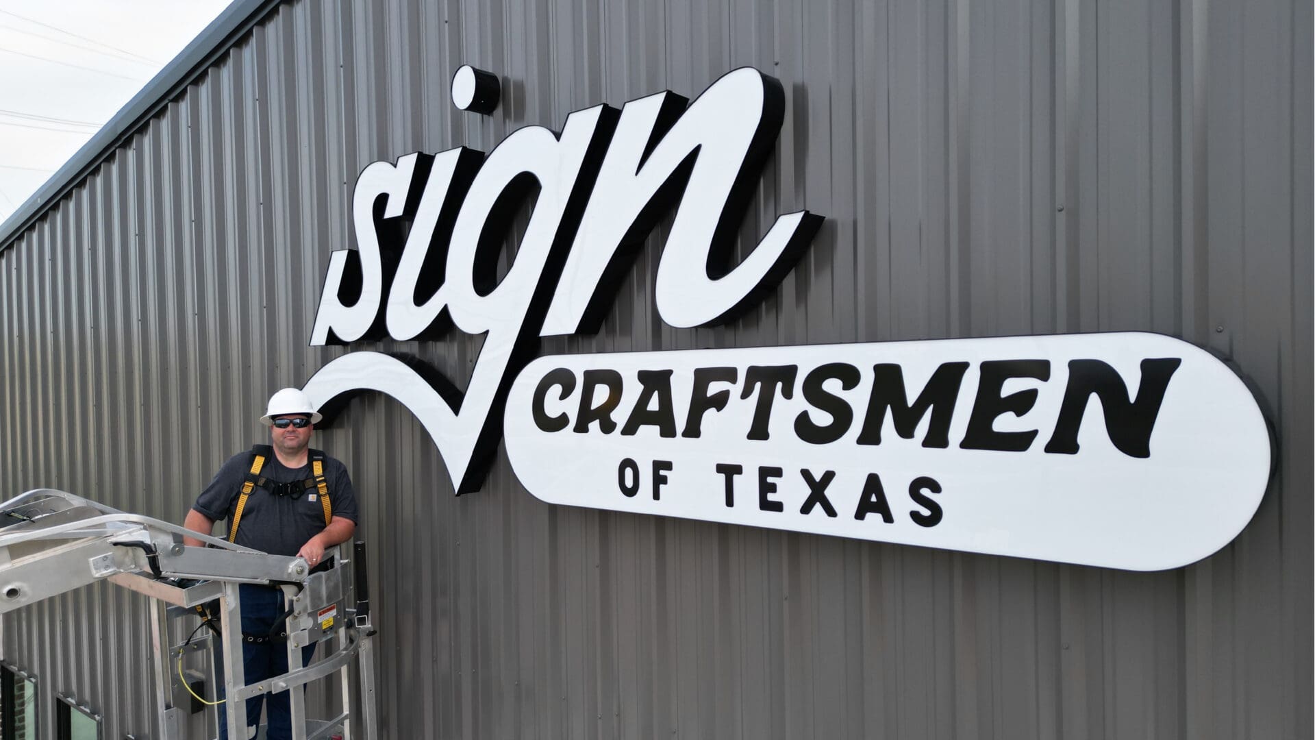 Worker on lift beside large Craftsmen sign